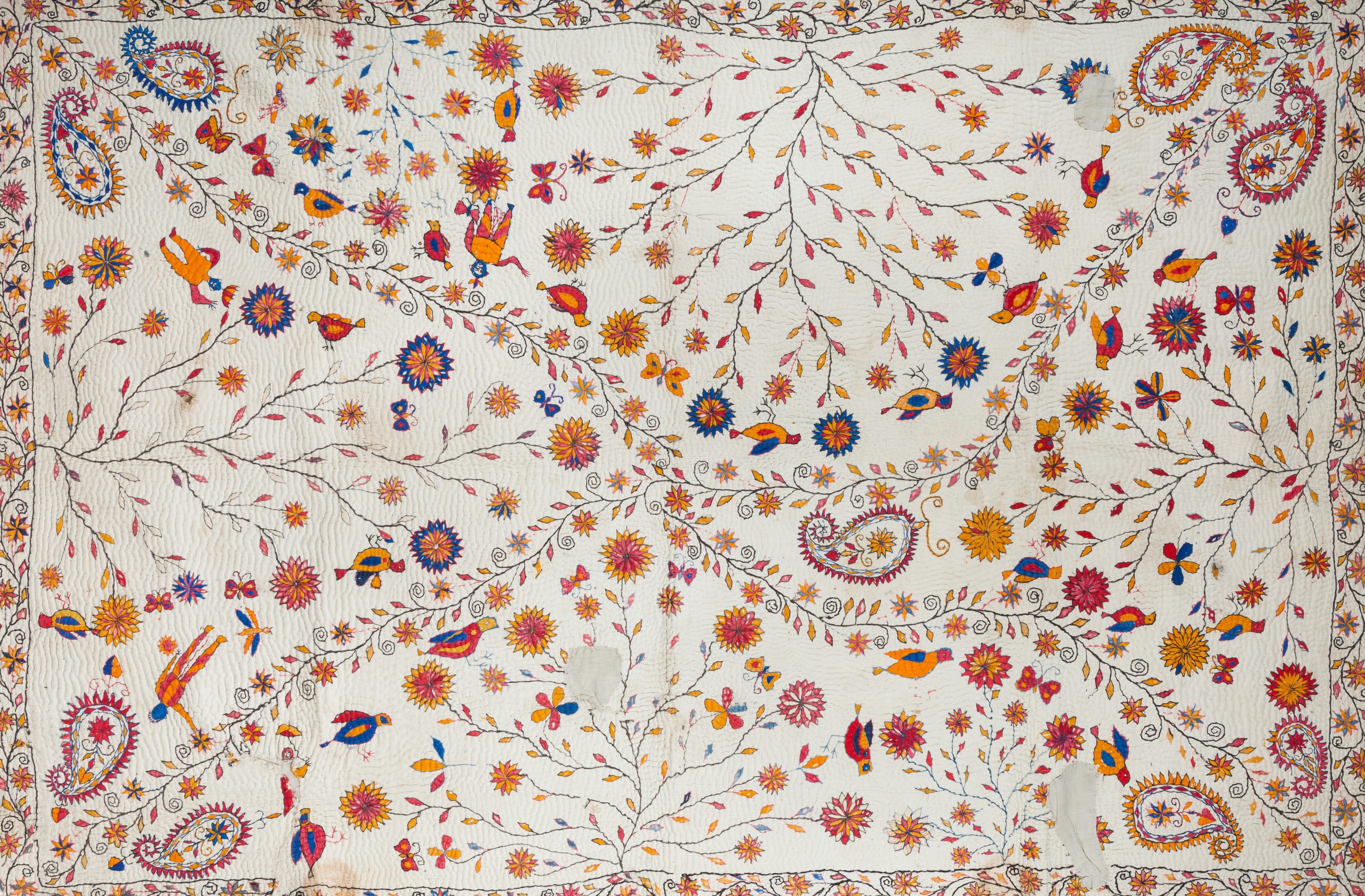 A white cloth embroidered in pink, blue, and fire shades with people and nature has a floral border.
