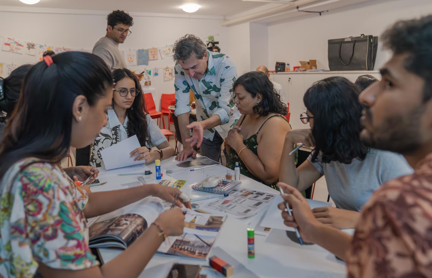 A person explaining something to a table of a group of people doing some crafts.